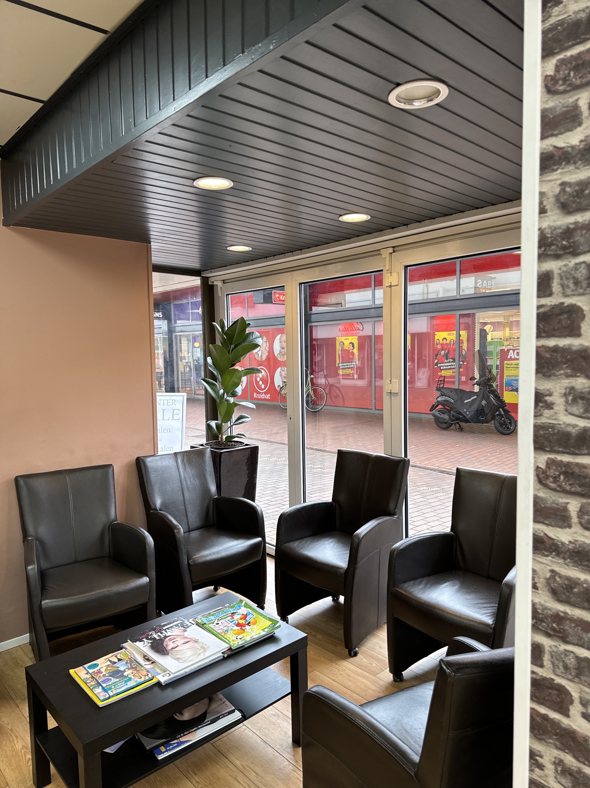 De wachtruimte met zwarte leren fauteuils en een tafel met tijdschriften bij het raam