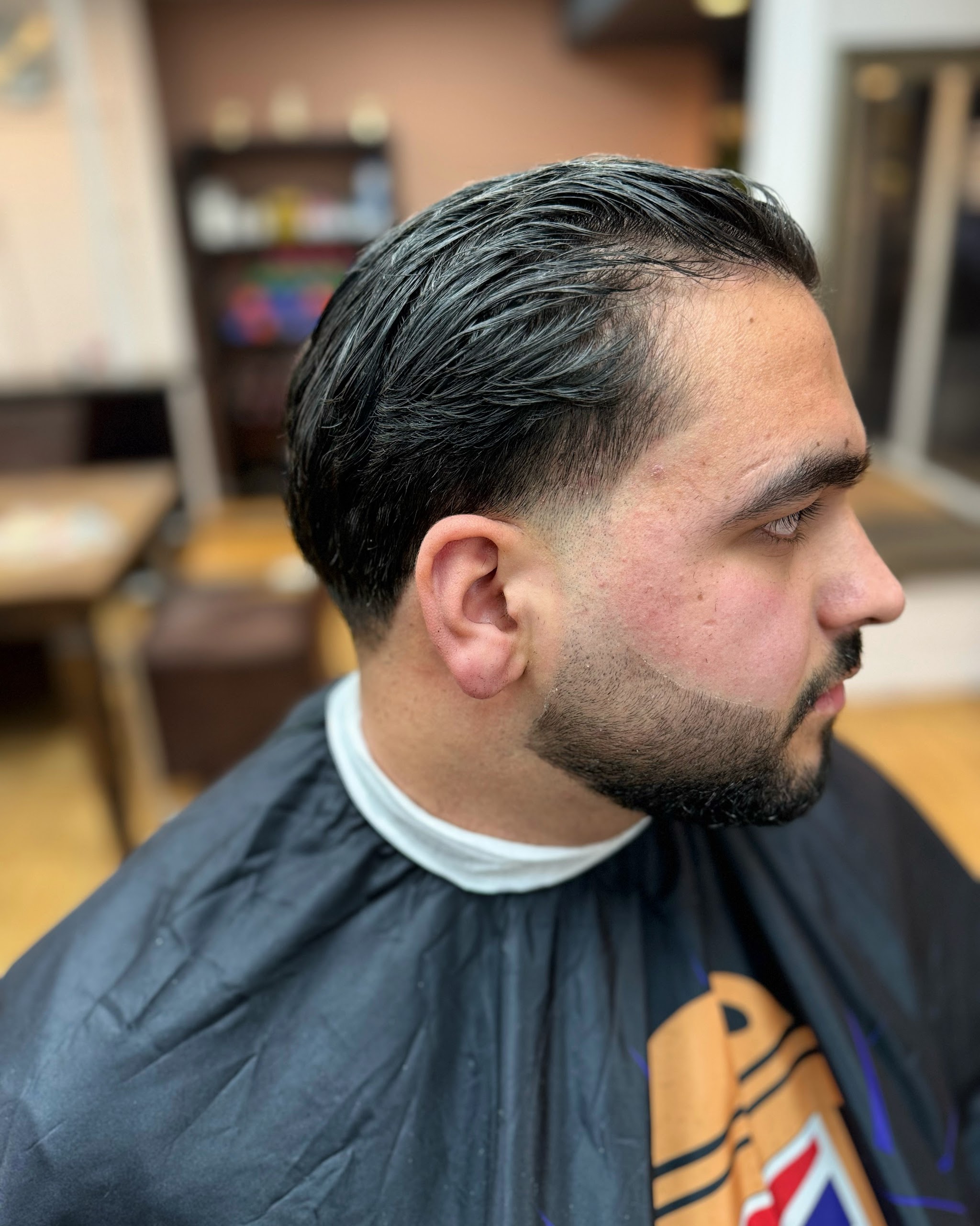 Klant van opzij met achterover gekamd haar en een verzorgde baard
